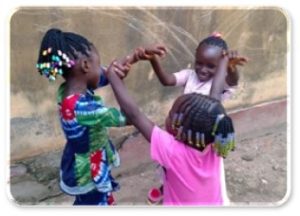 Trois petites filles qui rient et jouent ensemble en cercle, rituel pour cultiver la joie - Les Arbres du Bonheur